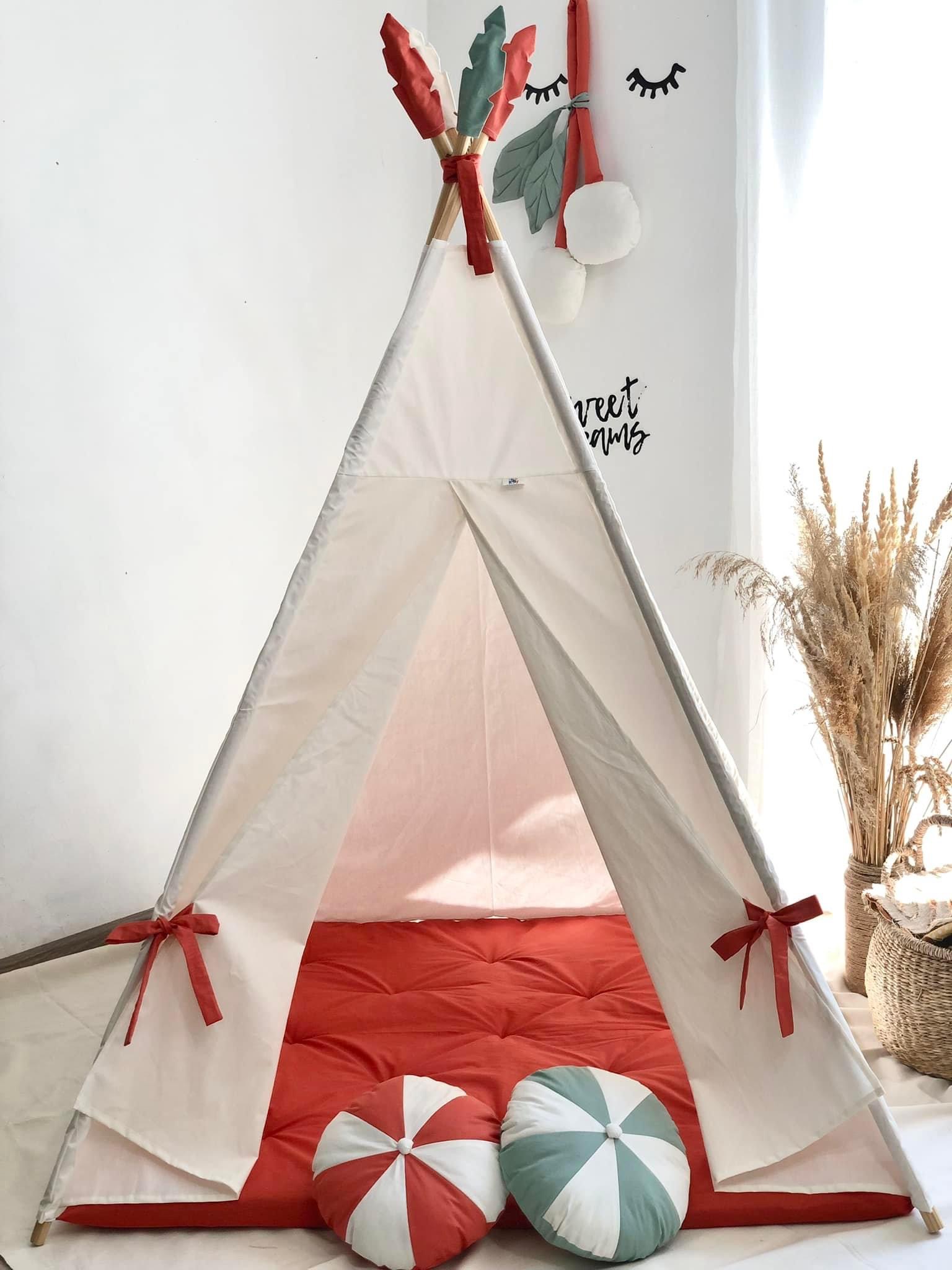 White tent with a fire-colored mattress and round pillows