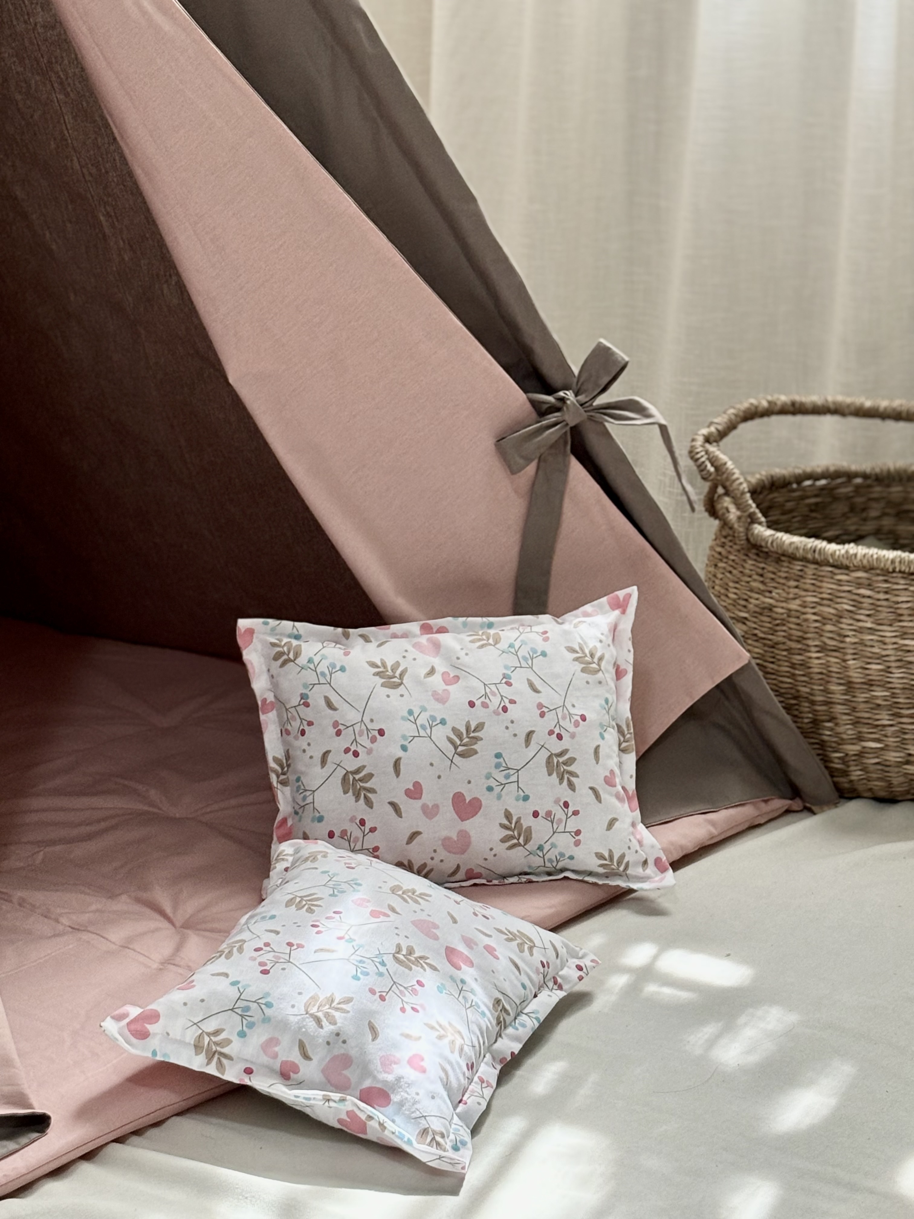 A brown tent with pink bedding and heart pillows