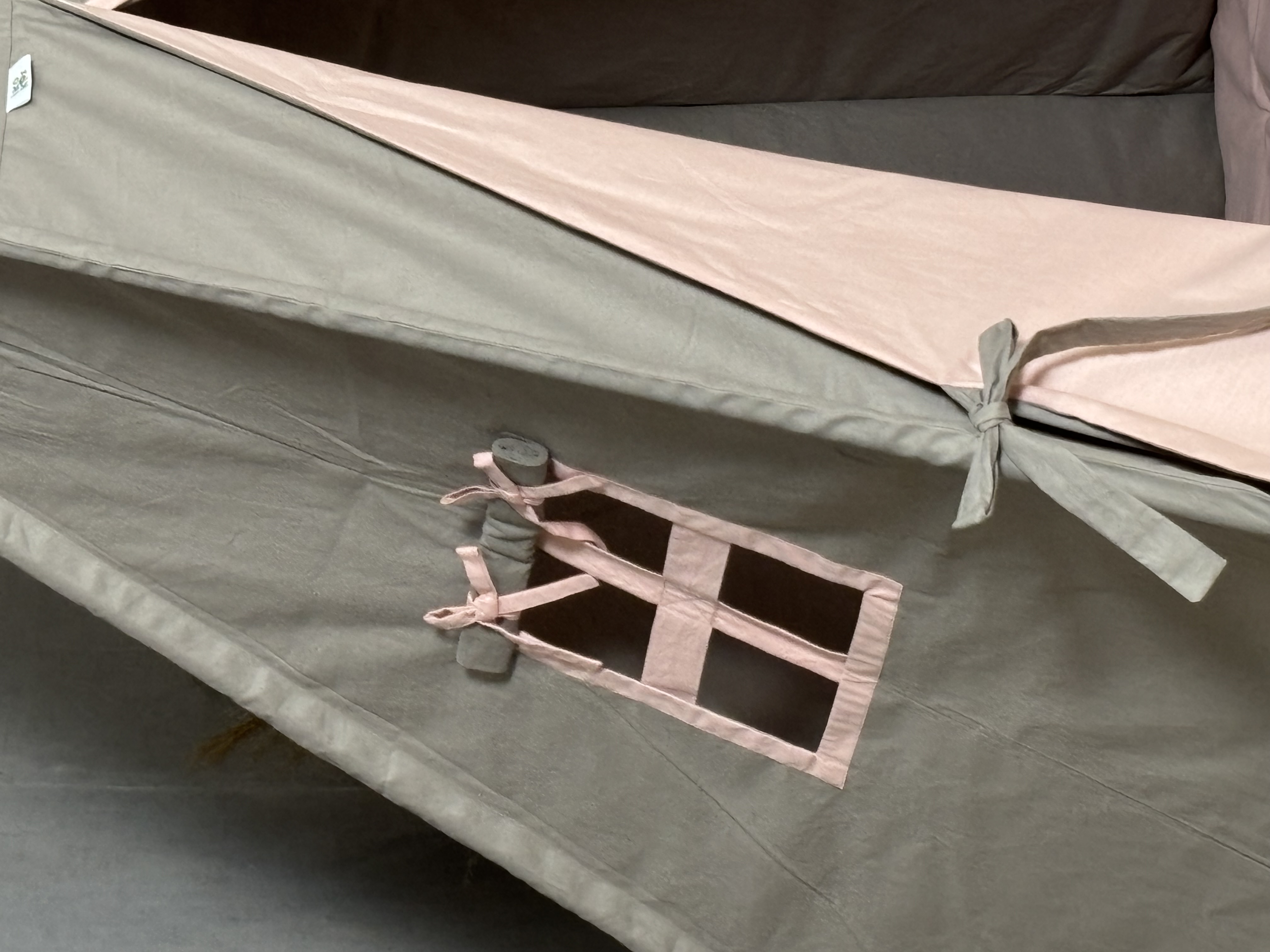 A brown tent with pink bedding and heart pillows